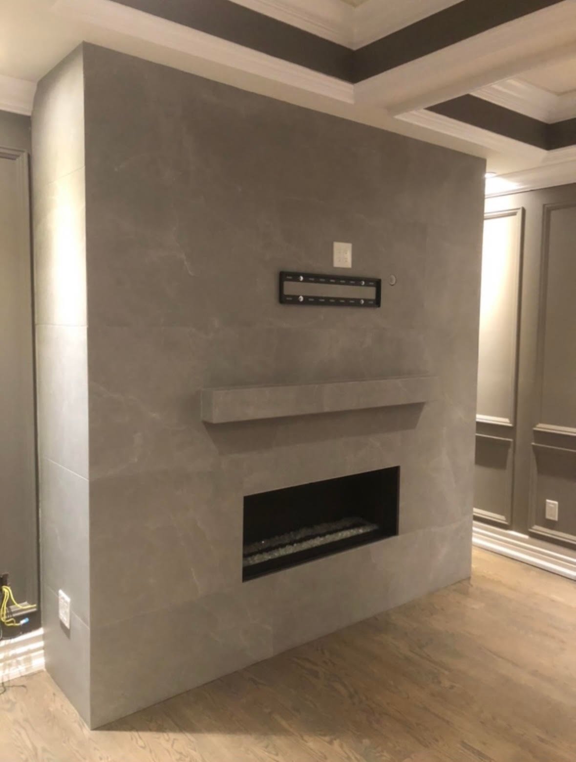 Modern fireplace feature wall with concrete finish, linear electric insert, and floating shelf in contemporary home interior