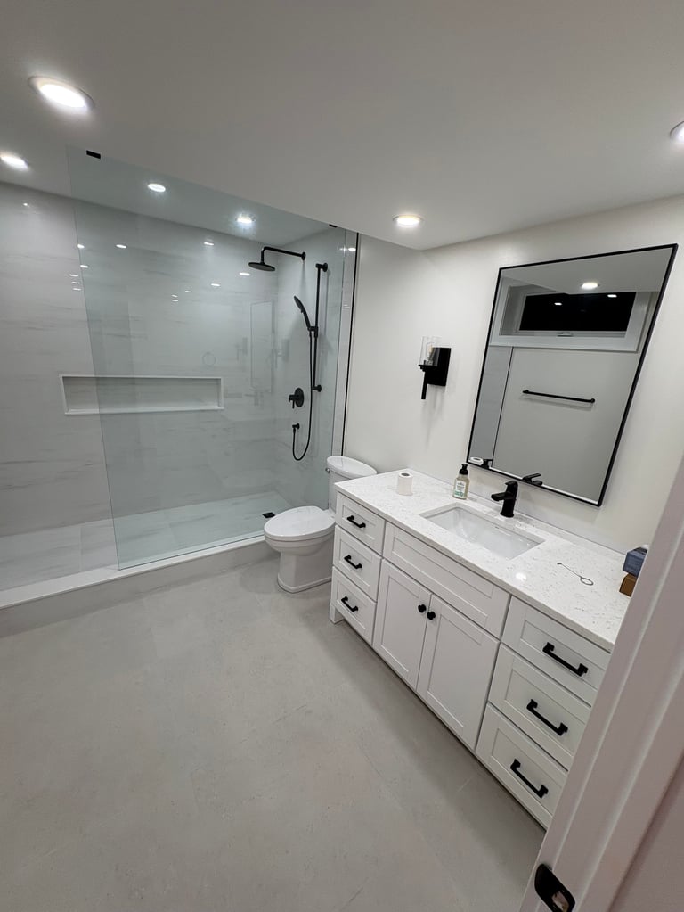 Modern bathroom with white vanity, large mirror, glass shower enclosure, and recessed lighting