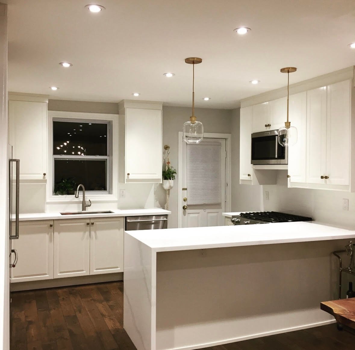 Modern kitchen with white cabinetry, quartz countertops, large island, and recessed lighting