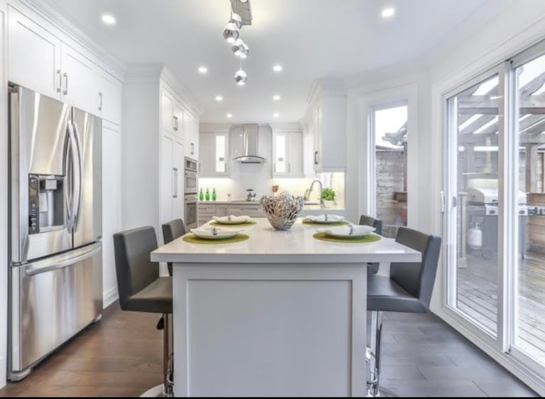 Modern kitchen with white cabinetry, stainless steel appliances, island seating, and French doors leading to outdoor patio