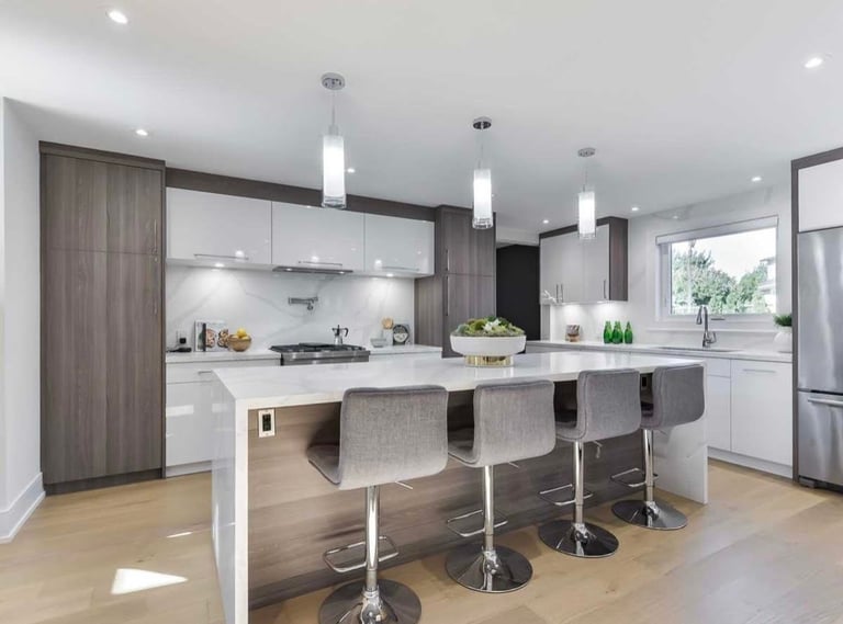 Modern kitchen with white cabinetry, dark wood accents, stainless steel appliances, and island seating with bar stools